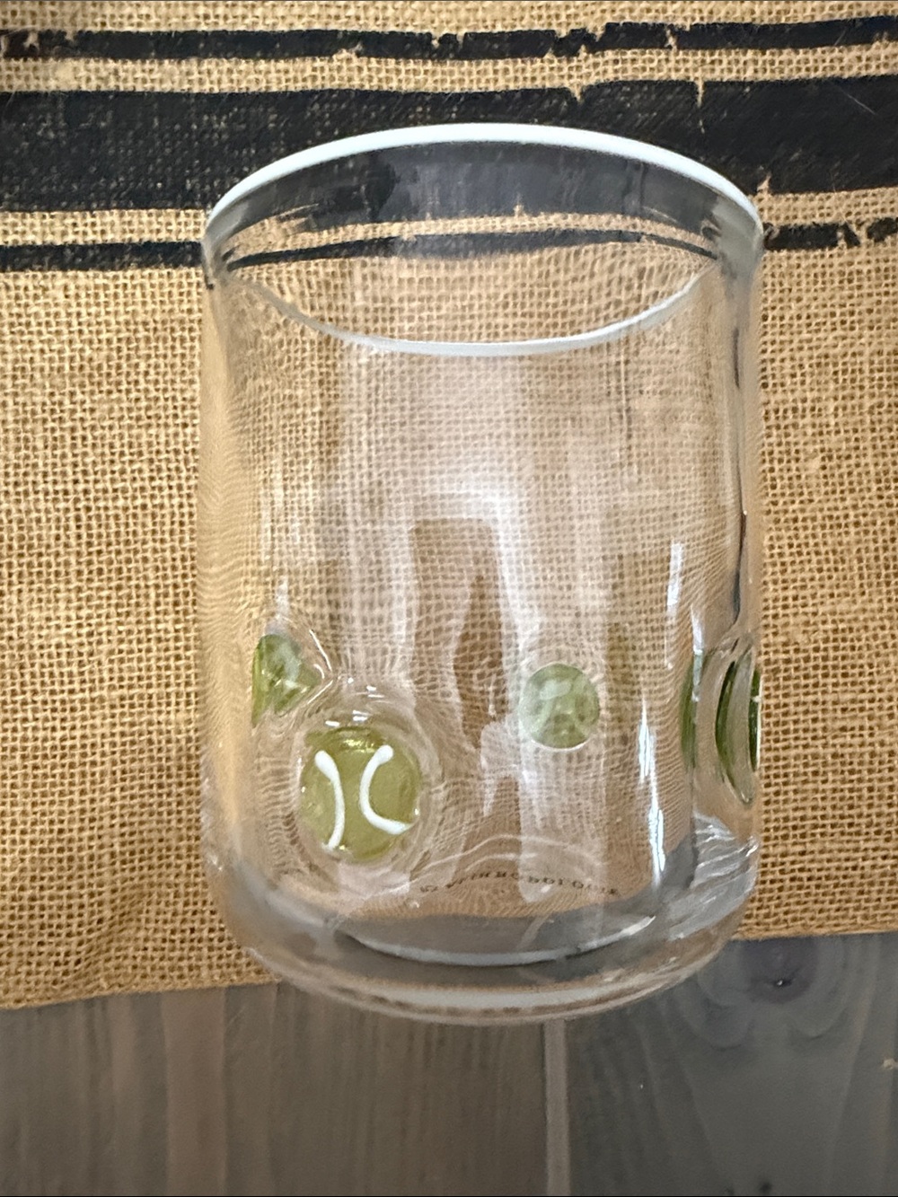 Anthropologie Clear drinking glass with yellow/green tennis ball accents.